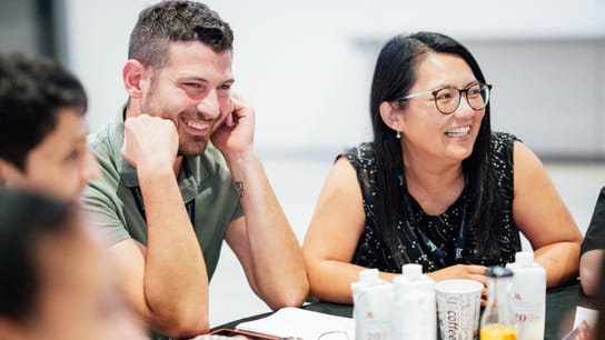 Multiple people smiling and in conversation at a table.