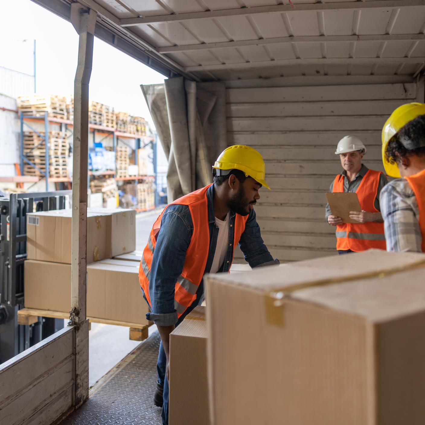 Grupo de trabajadores latinoamericanos cargando un camión mientras trabajan para una empresa de transporte de carga.