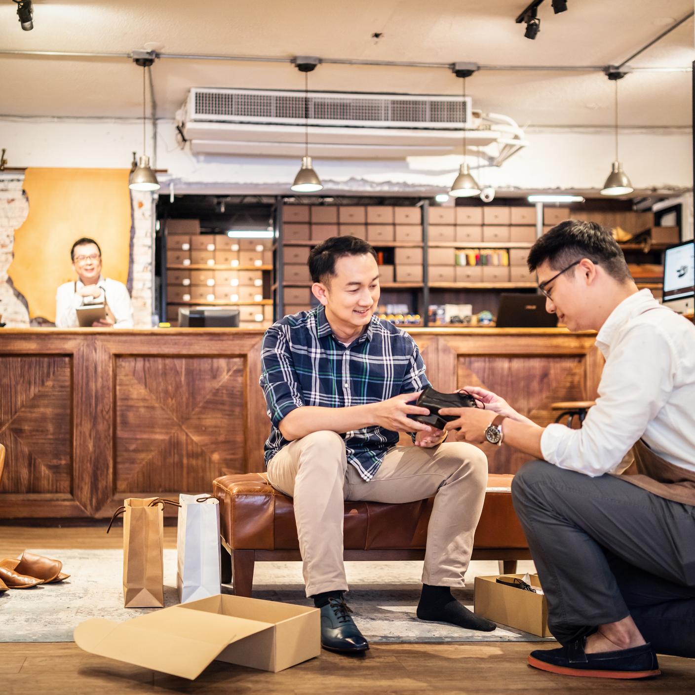Een verkoper stelt nieuwe schoenen voor aan een klant in een schoenenwinkel.