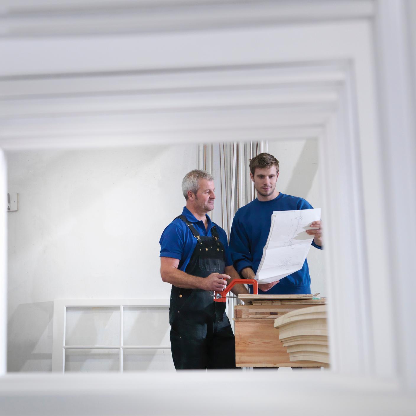 View of workers through window frames in joinery (cropped).