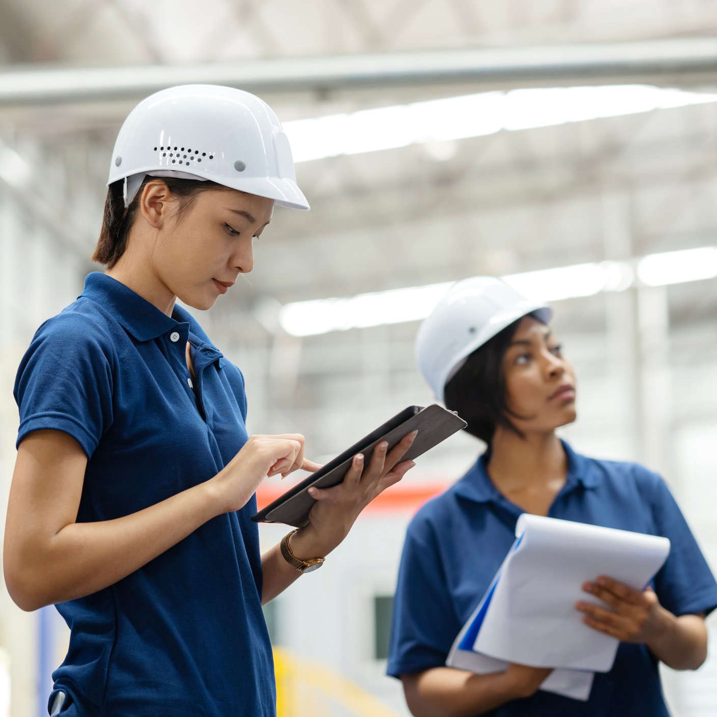 Reducing Downtime and Improving Machine Health with Predictive Maintenance in Manufacturing Operations. Diversity teams of Maintenance Engineers using a tablet computer to machine health and monitoring via a mobile application on a production line factory floor.