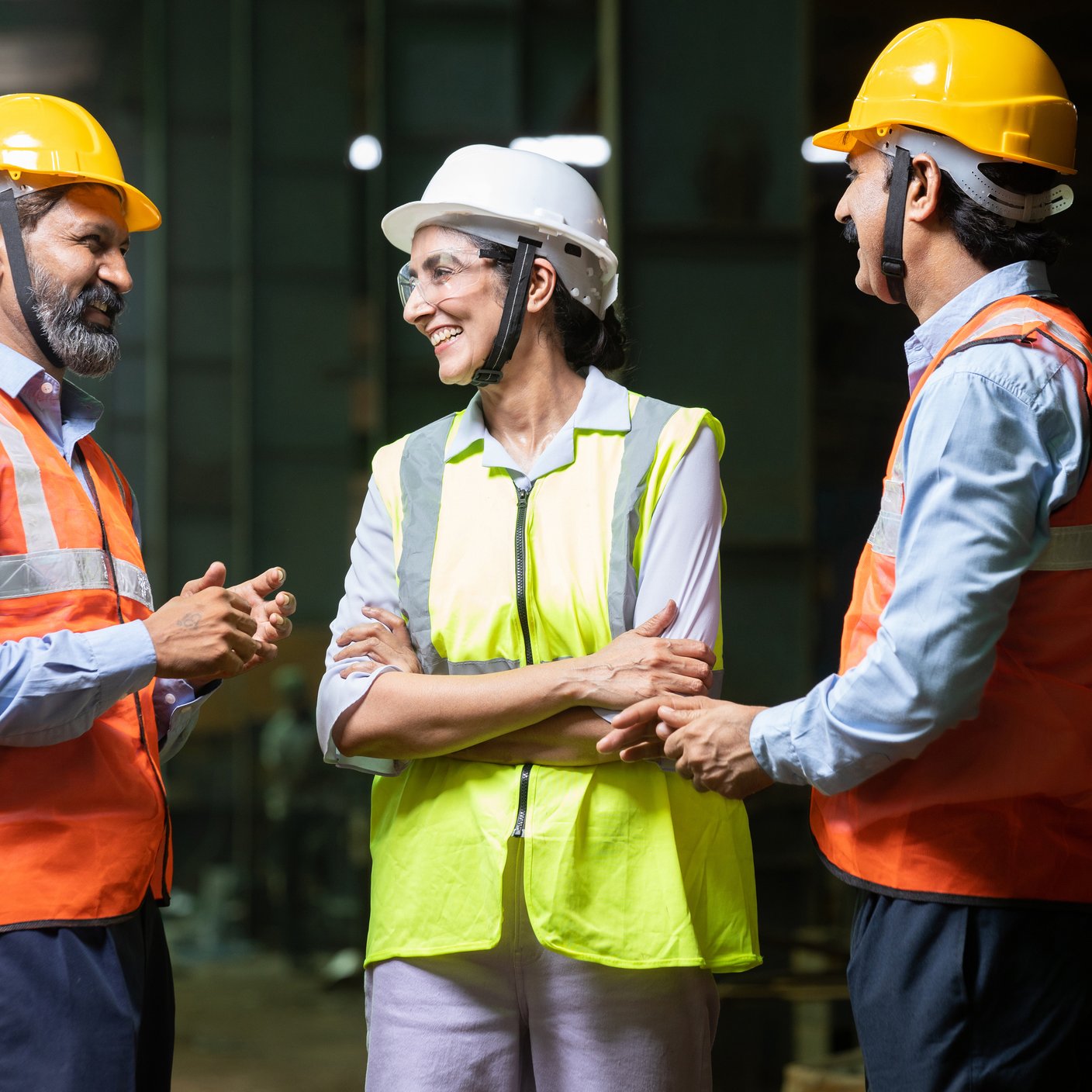 Team of happy indian engineers wearing safety hard hat and vest.