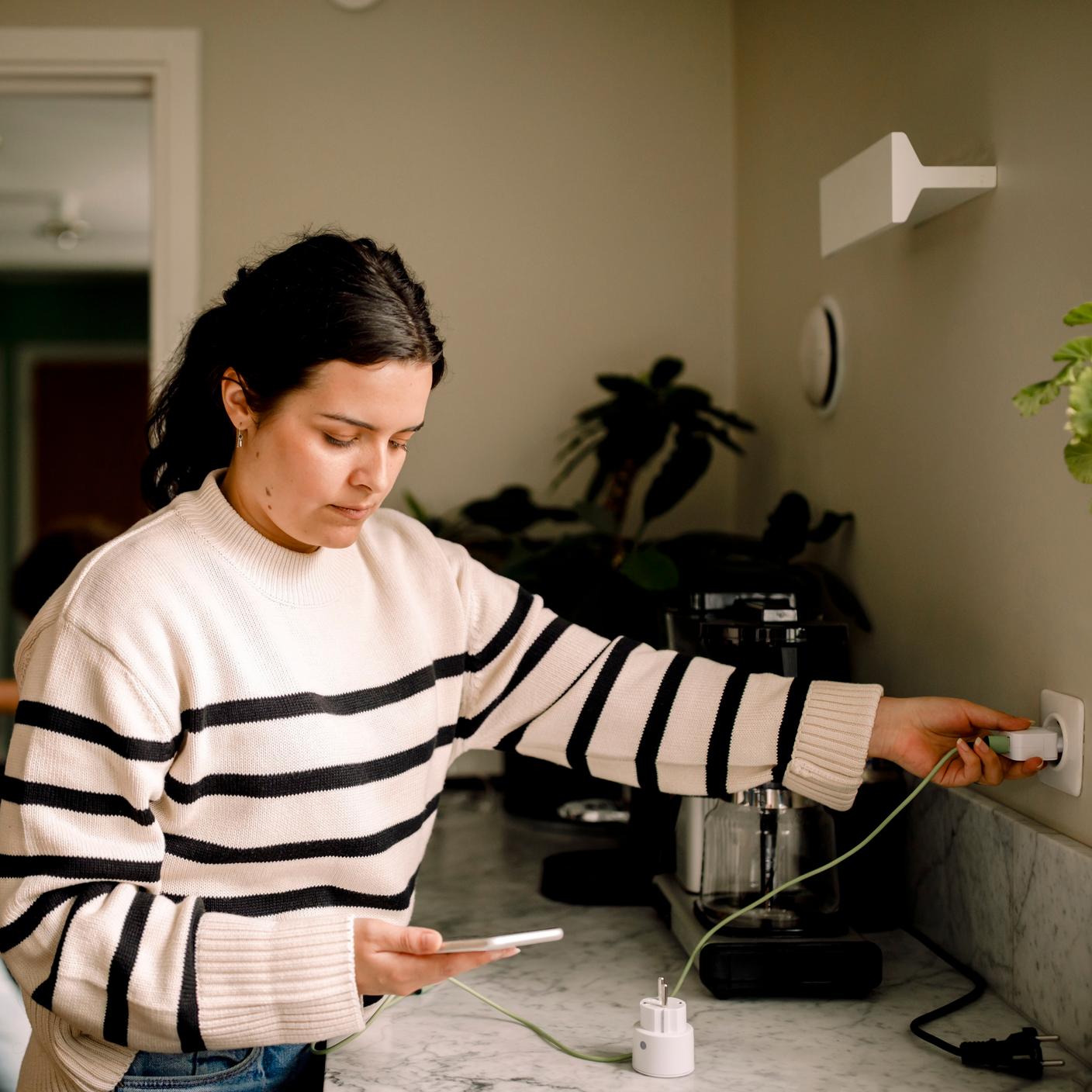 Une femme chargeant son téléphone portable dans la cuisine