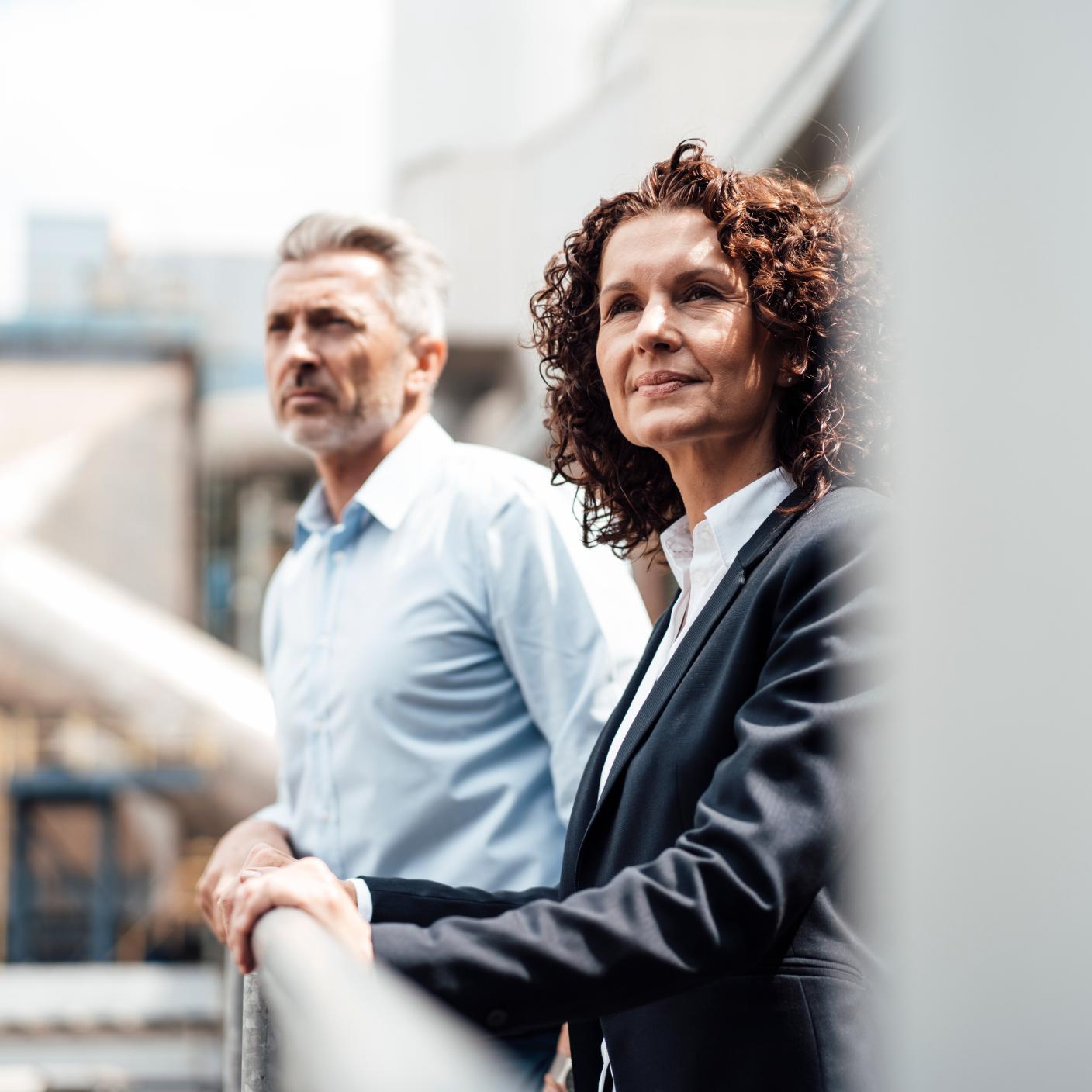 Thoughtful businesswoman standing with colleague by railing