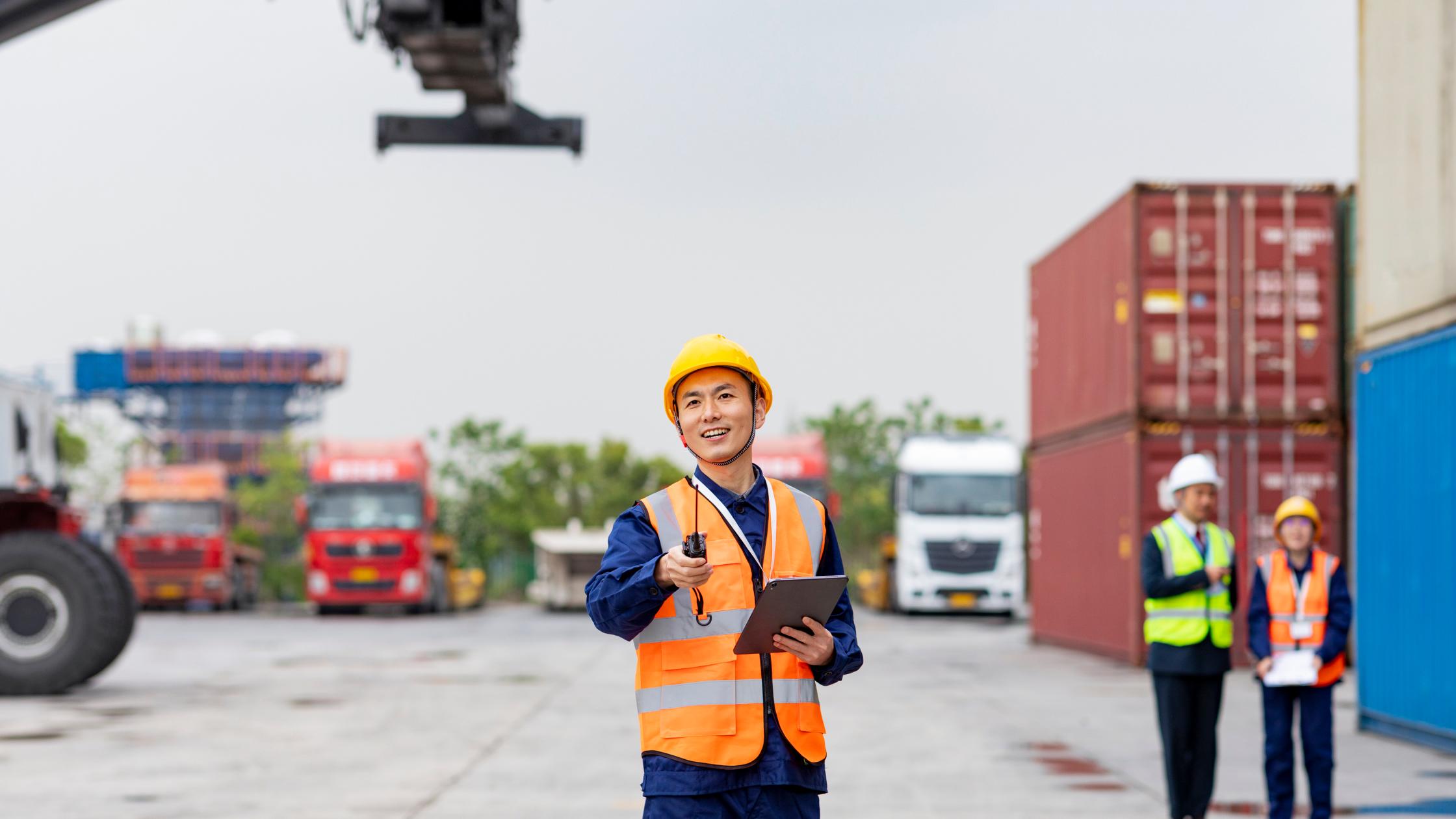 Nam kỹ sư kiểm soát vận chuyển đang đứng trước container hàng hóa.
